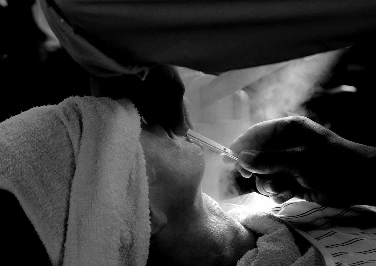 A straight razor shave under a towel, with steam rising
