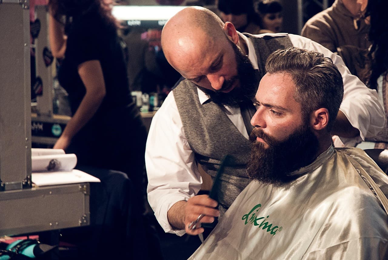 A barber shaping a customer’s full beard