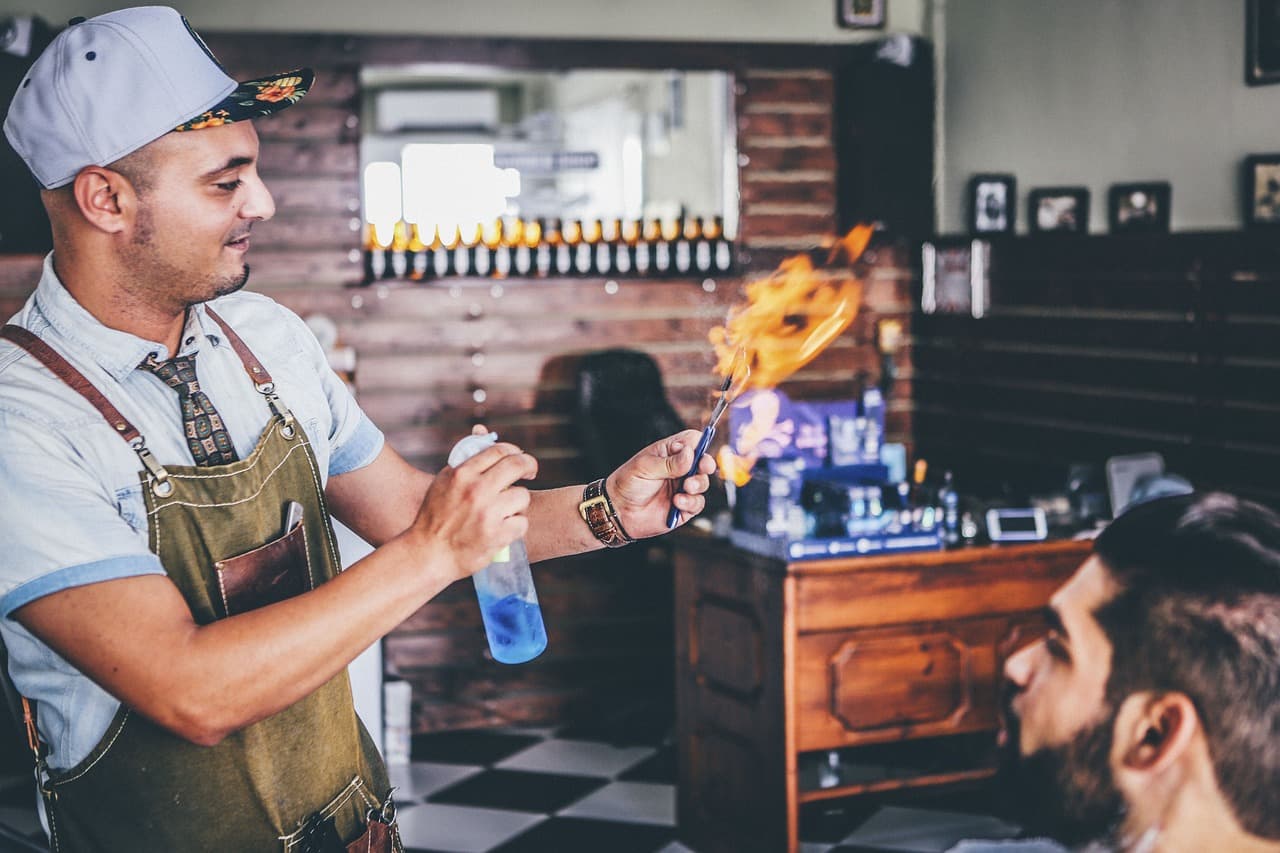 A barber sending up a flame from a lighter and a spray bottle