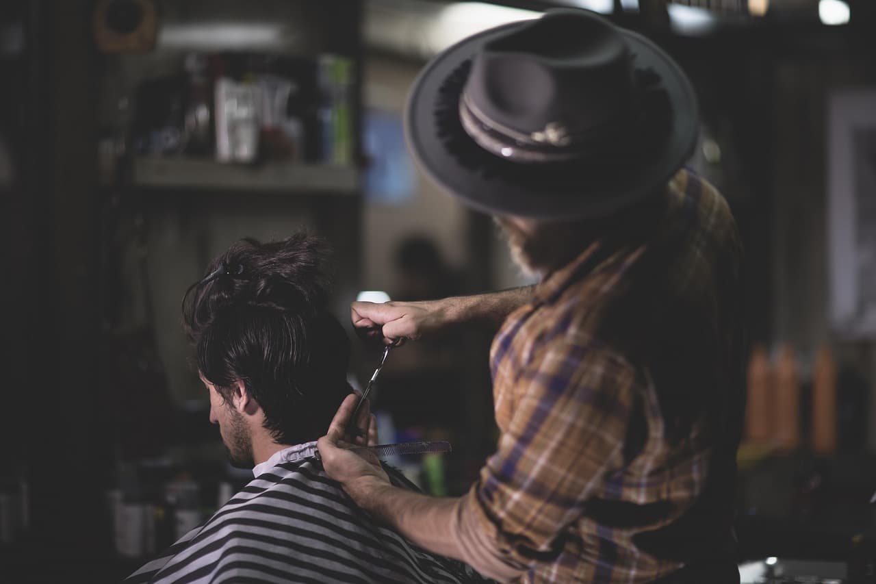 A barber cutting a customer’s hair with scissors