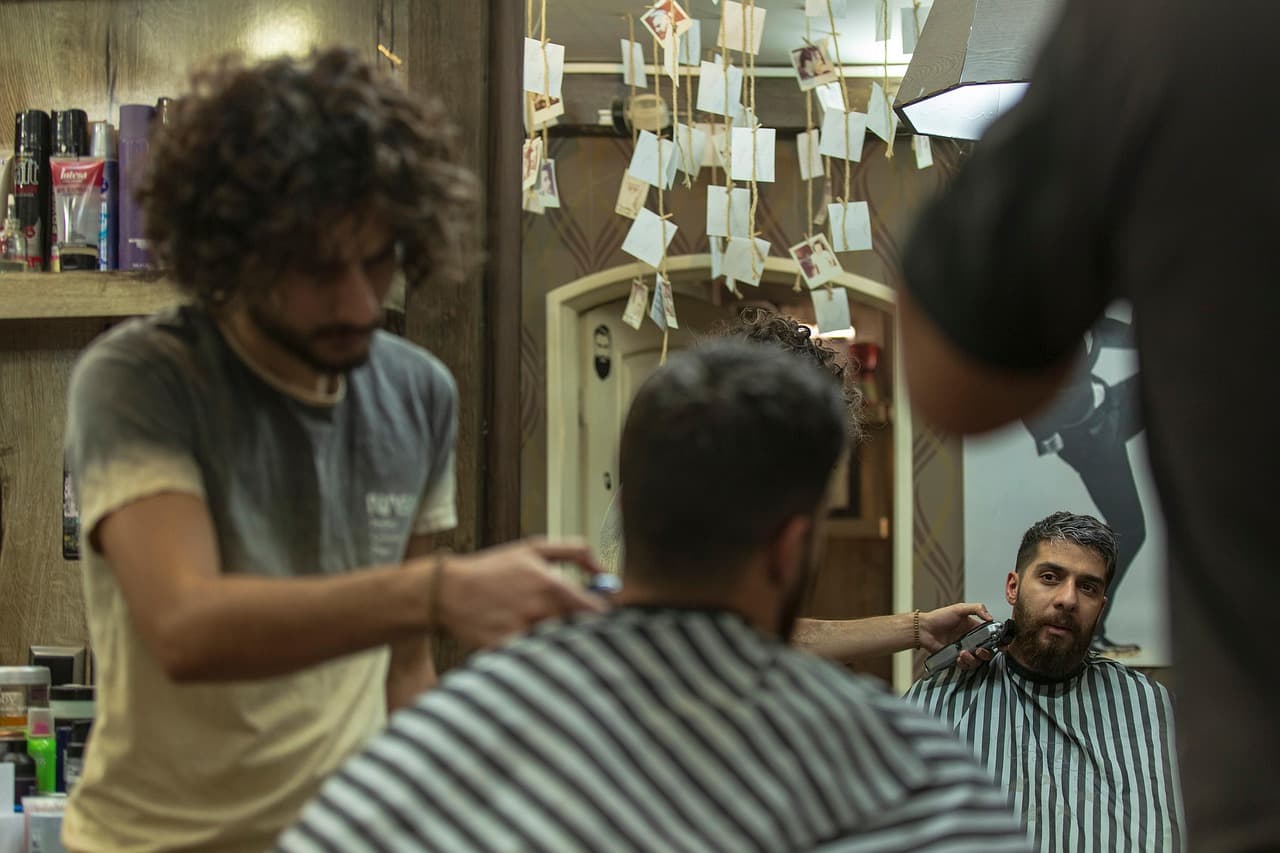 A barber taking the clippers to a customer, seen in the mirror