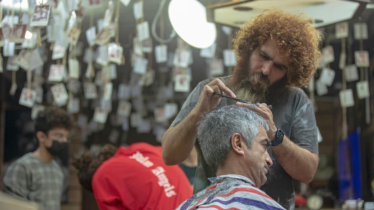 A barber combing out a customer’s grey hair before the scissors